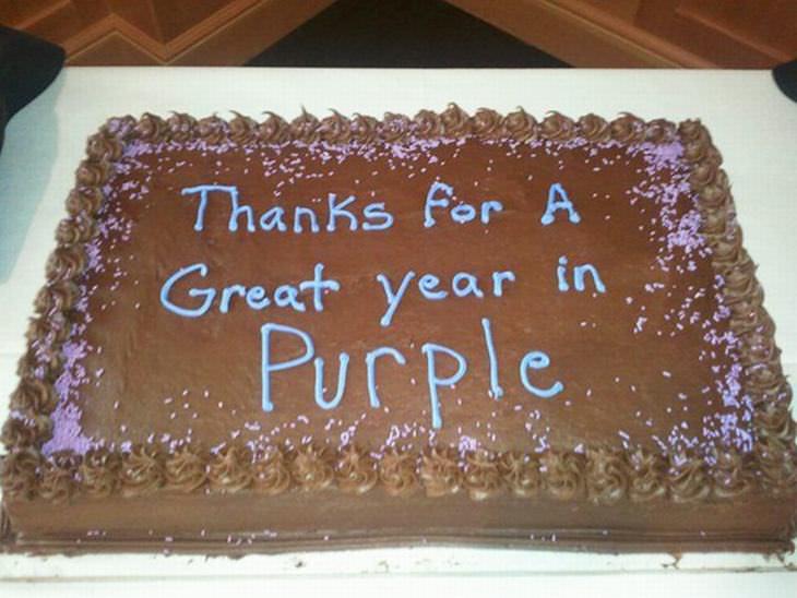 A chocolate cake with sprinkles and the text "Thanks For A Great year in Purple" written in blue icing across the top