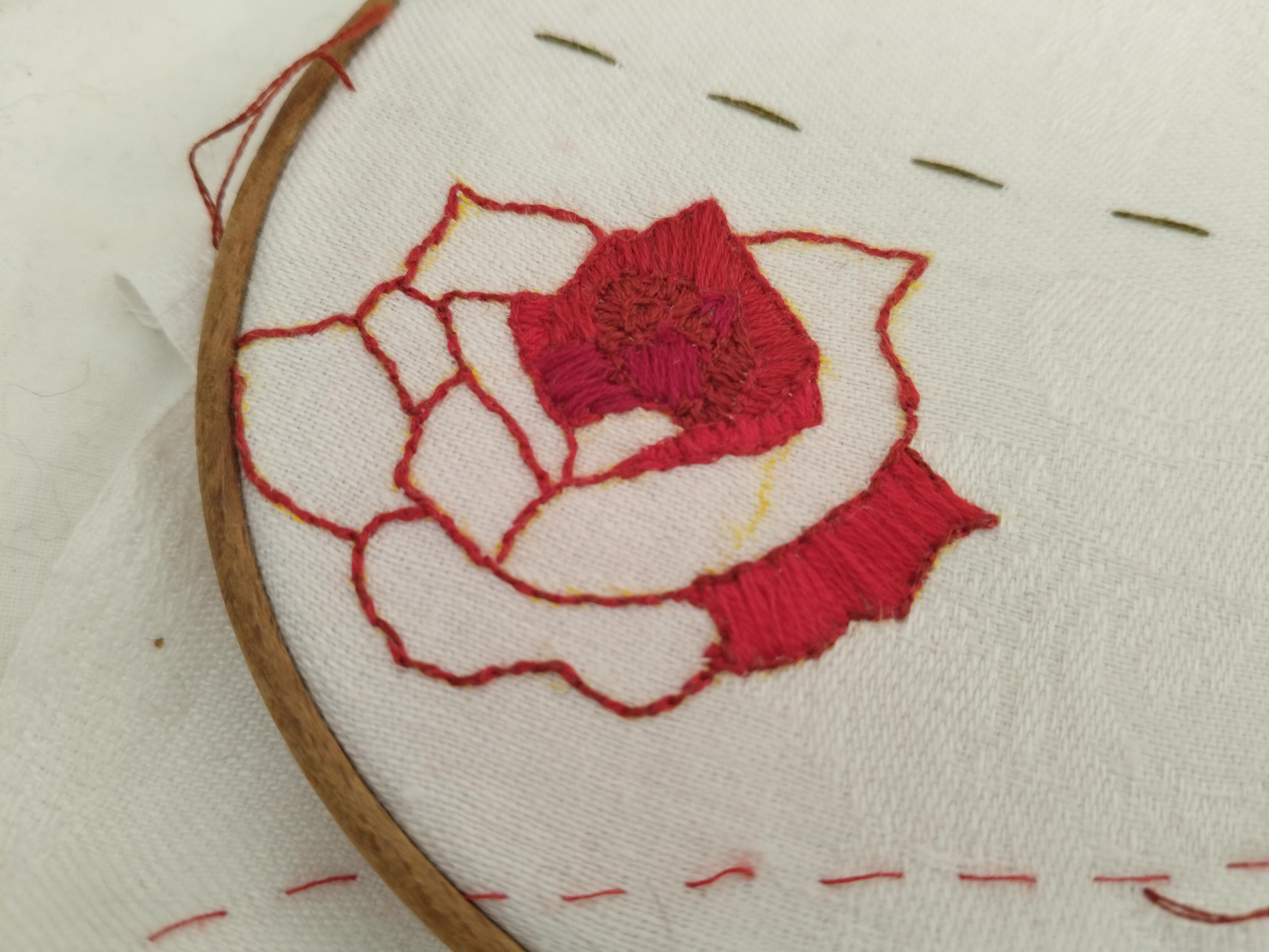 an embroidered outline of a red rose, which has been partially filled in with 4 different shades of red that don't go super well together.