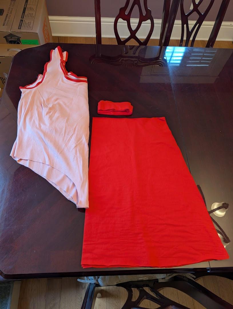 A work-in-progress of a woman's swimsuit in pink jersey knit fabric with red trim and the pieces for a matching red skirt.