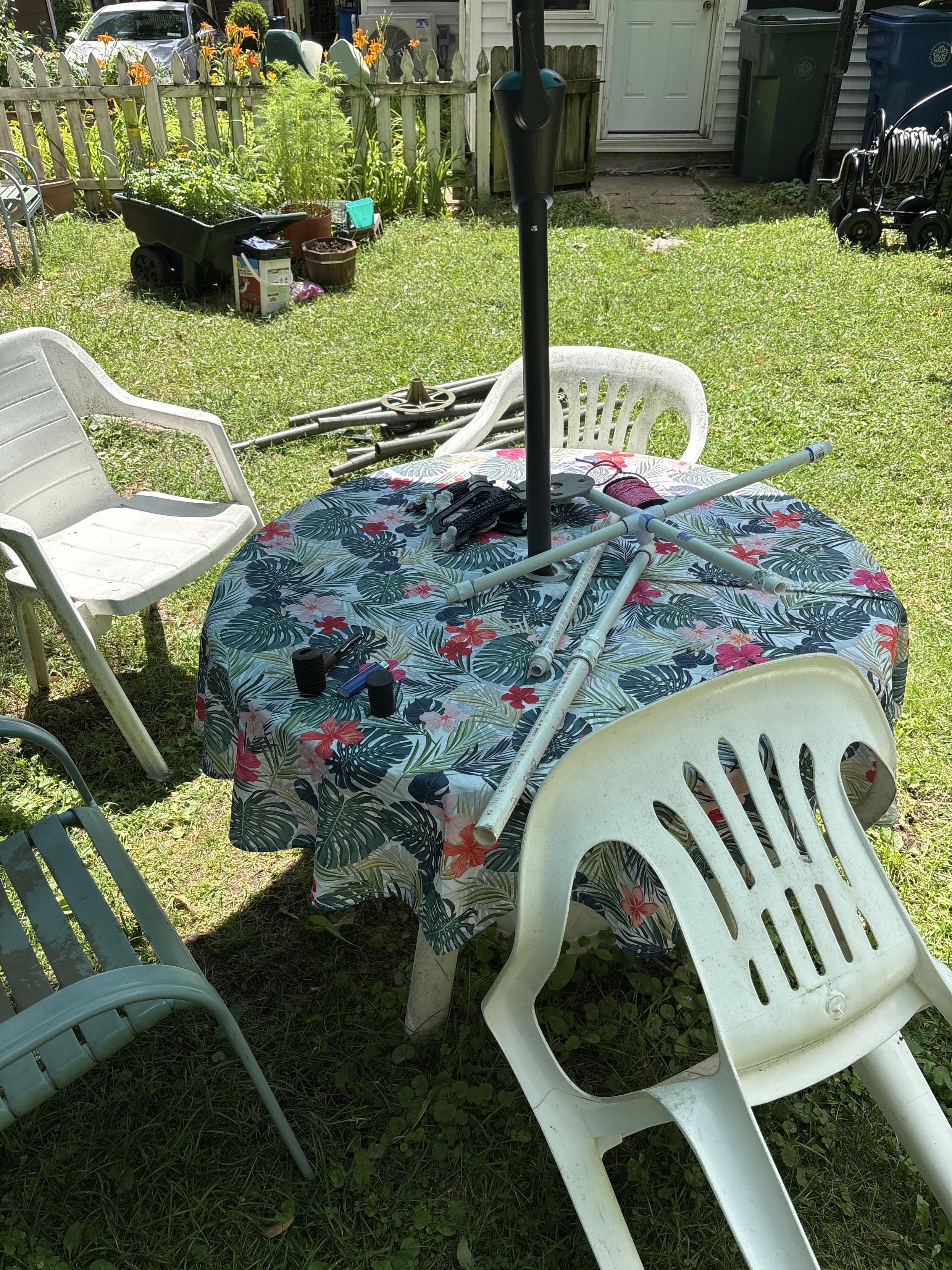 pieces of PVC quad loop spreaders on backyard tabke in foreground, sections of fiberglass mast element on ground behind table