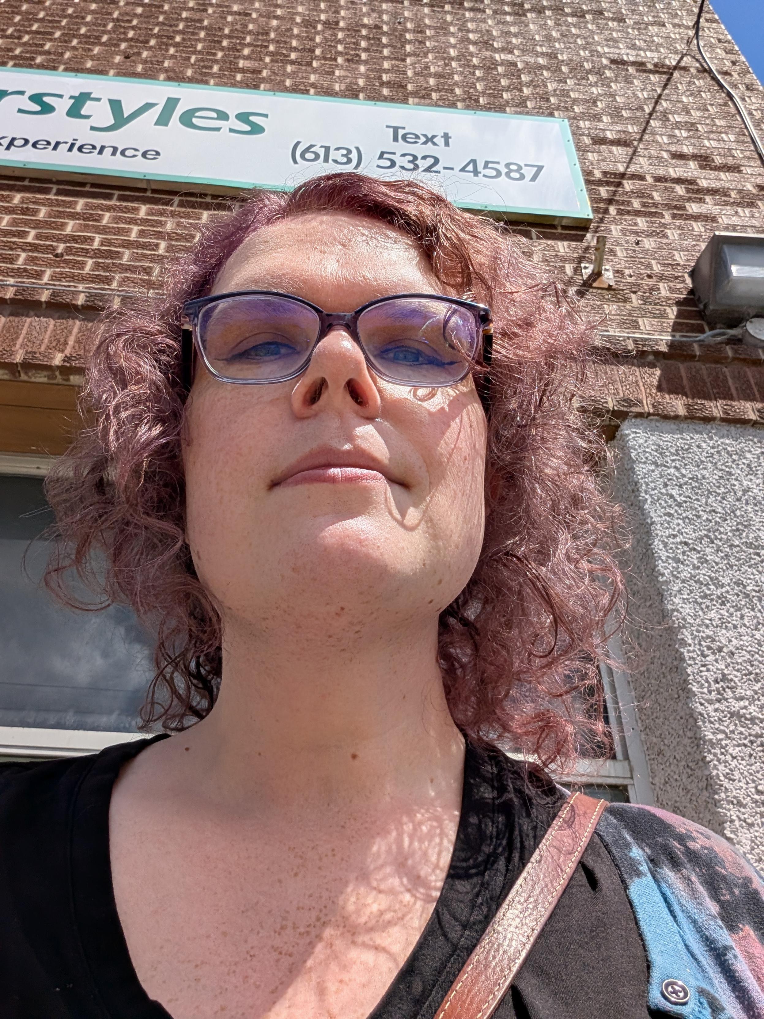 White woman with purple hair looking down at you