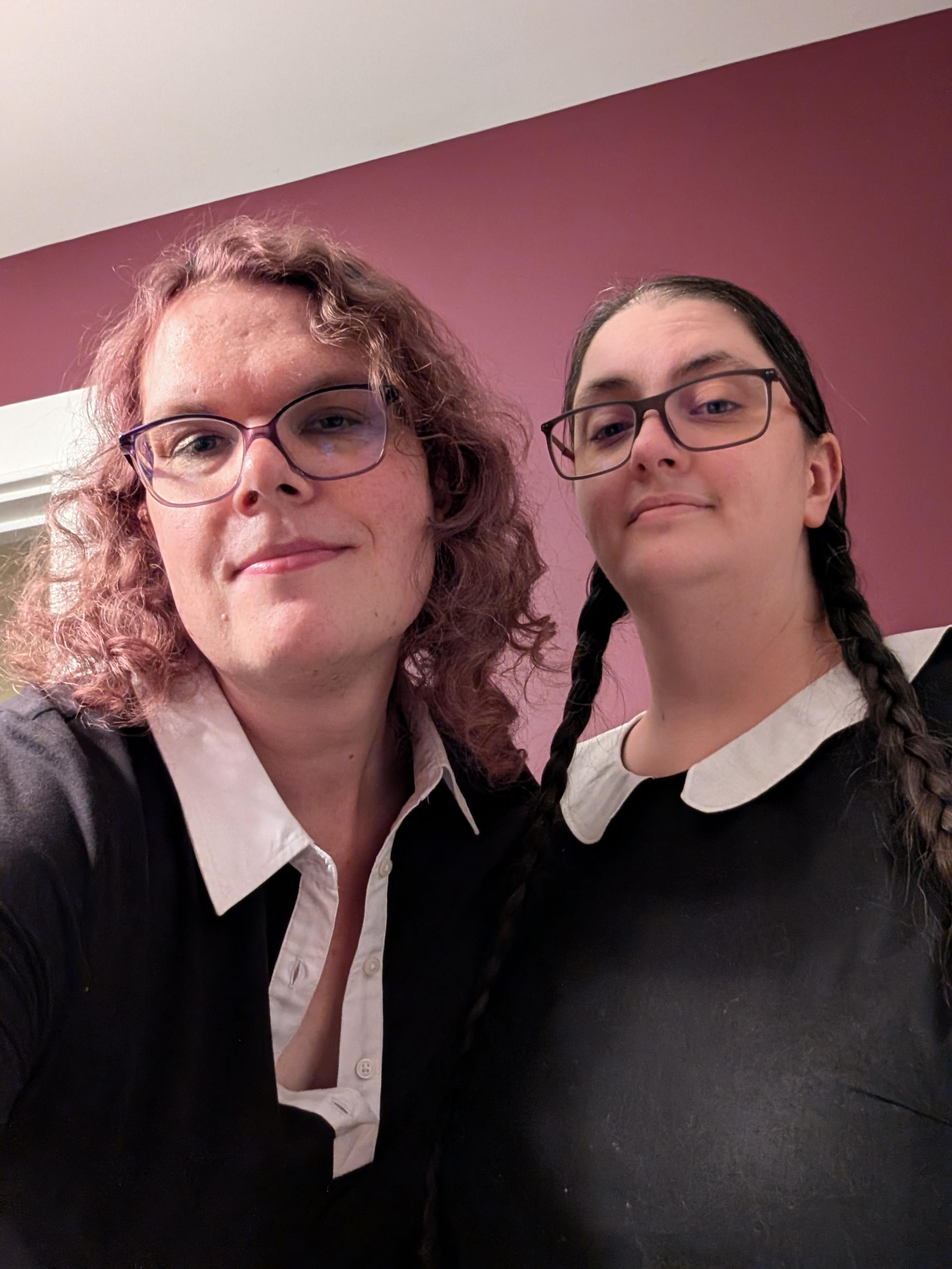 Christine and Morgan in black dresses with white trim, looking down at you
