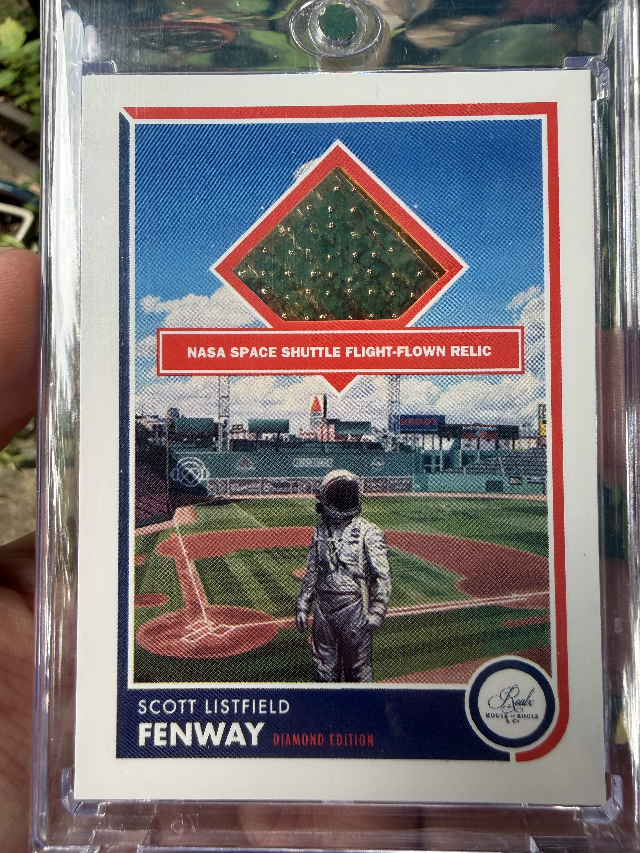 A trading card featuring an image of an astronaut superimposed over Fenway Park. There is a diamond-shaped area near the top containing a reflective metallic piece, labeled “NASA SPACE SHUTTLE FLIGHT-FLOWN RELIC”. The bottom of the card is labeled “SCOTT LISTFIELD / FENWAY / DIAMOND EDITION” and bears the House of Roulx logo in the right corner.
