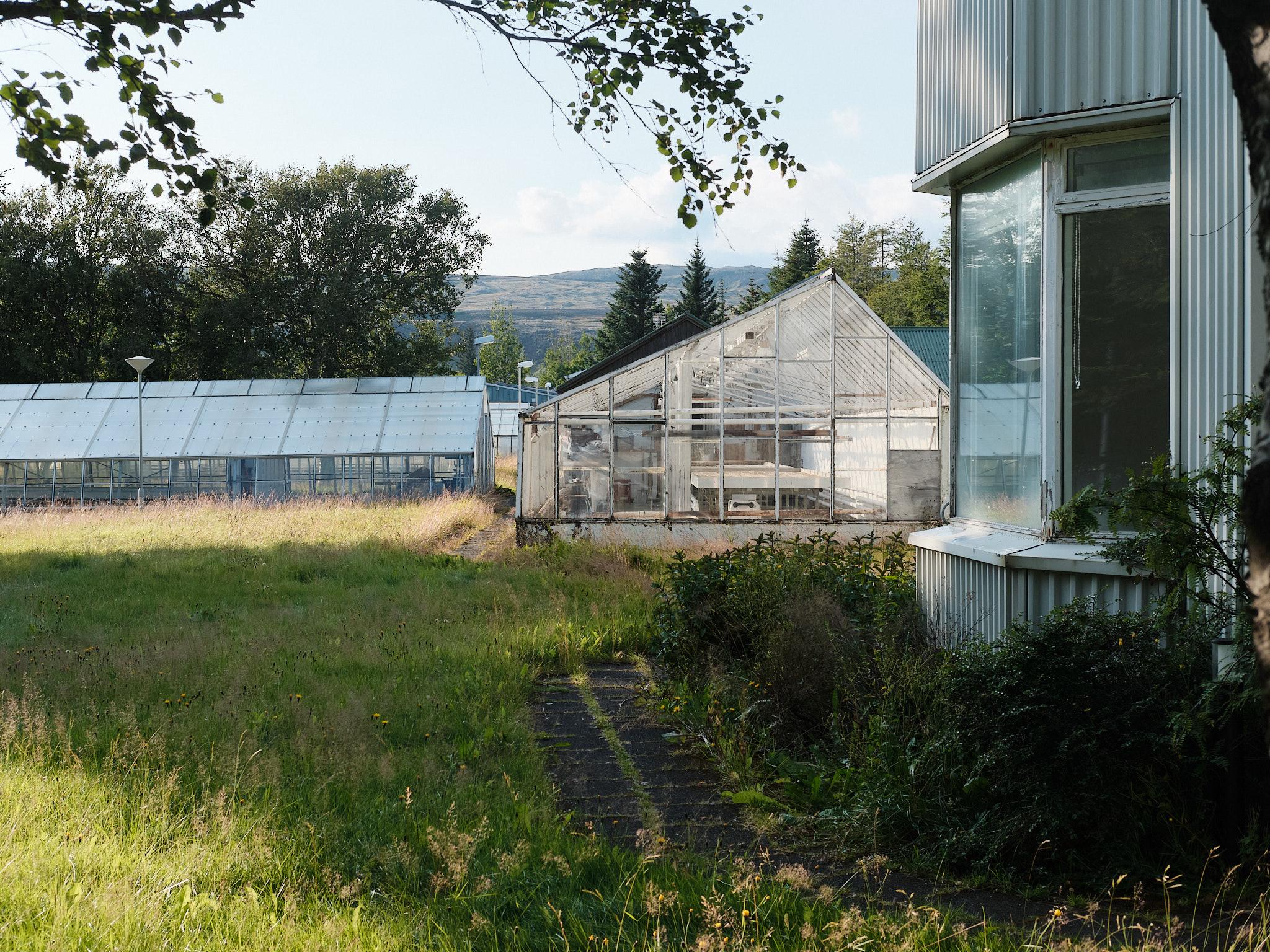 An old house, next to two empty commercial greenhouses
