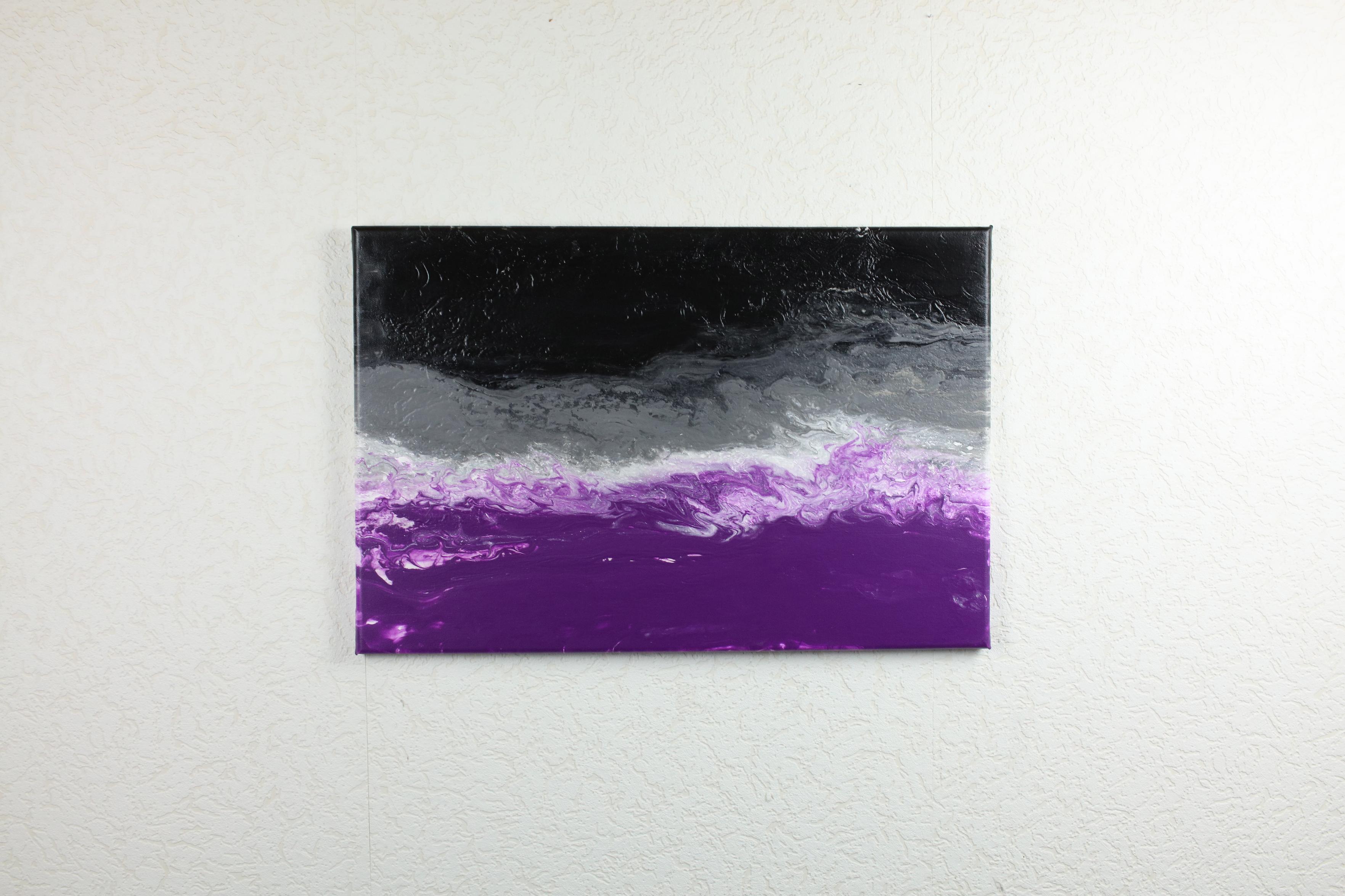a painting of an ace pride flag where the color layers look like clouds on top of each other. It is hanging on a white structured wall