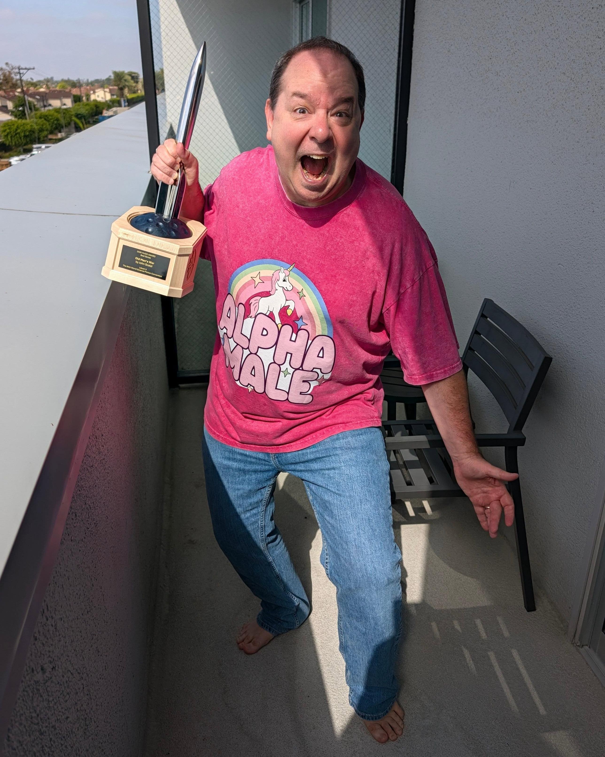 Me in a pink shirt with a unicorn and rainbow that says "alpha male" on it wielding a Hugo like a maniac, with an expression that makes me look like a deranged squirrel
