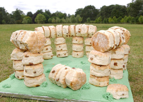 The structure replicates the stone circle and lintels at Stone Henge (the horizontal "stones" balancing on top of the vertical stacks) using stacks of baked scones, arranged on a green frosting base to mimic the grassy Salisbury Plain.