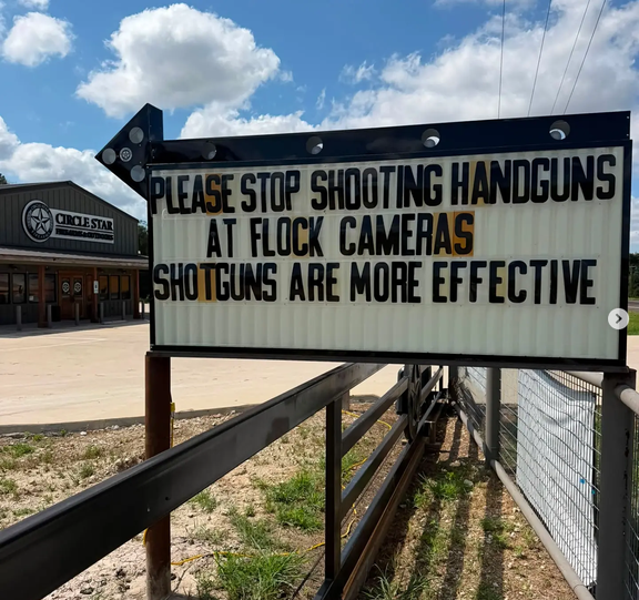 Outside Circle Star firearms in Houston, there is a sign that says "PLEASE STOP SHOOTING HANDGUNS AT FLOCK CAMERAS. SHOTGUNS ARE MORE EFFECTIVE."