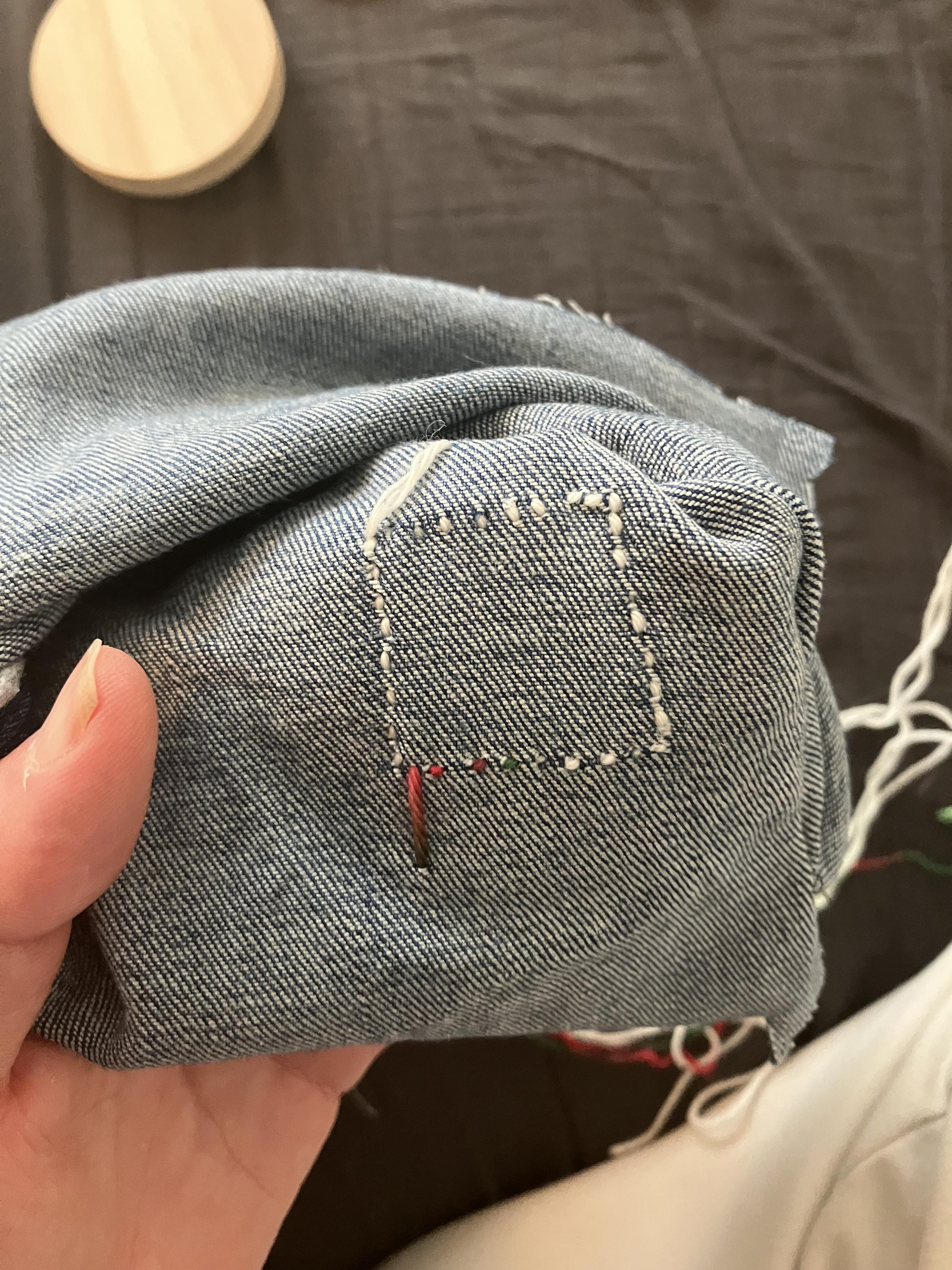 Back of the patch. The outline of a wobbly square in tiny stitches. If this was a mend instead of practice there would be a hole under it.