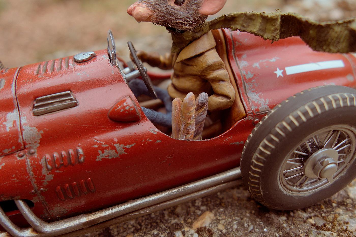 Rat racer figure riding a model car. Close up of baguettes.