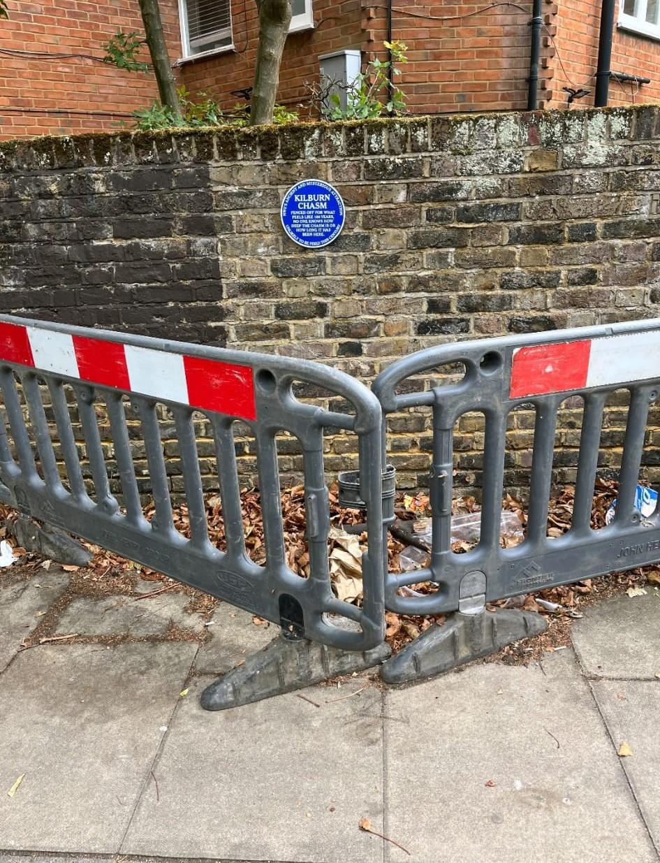 Longer distance view of the plaque with two barriers in front. The chasm itself unfortunately is mostly invisible under a pile of leaves
