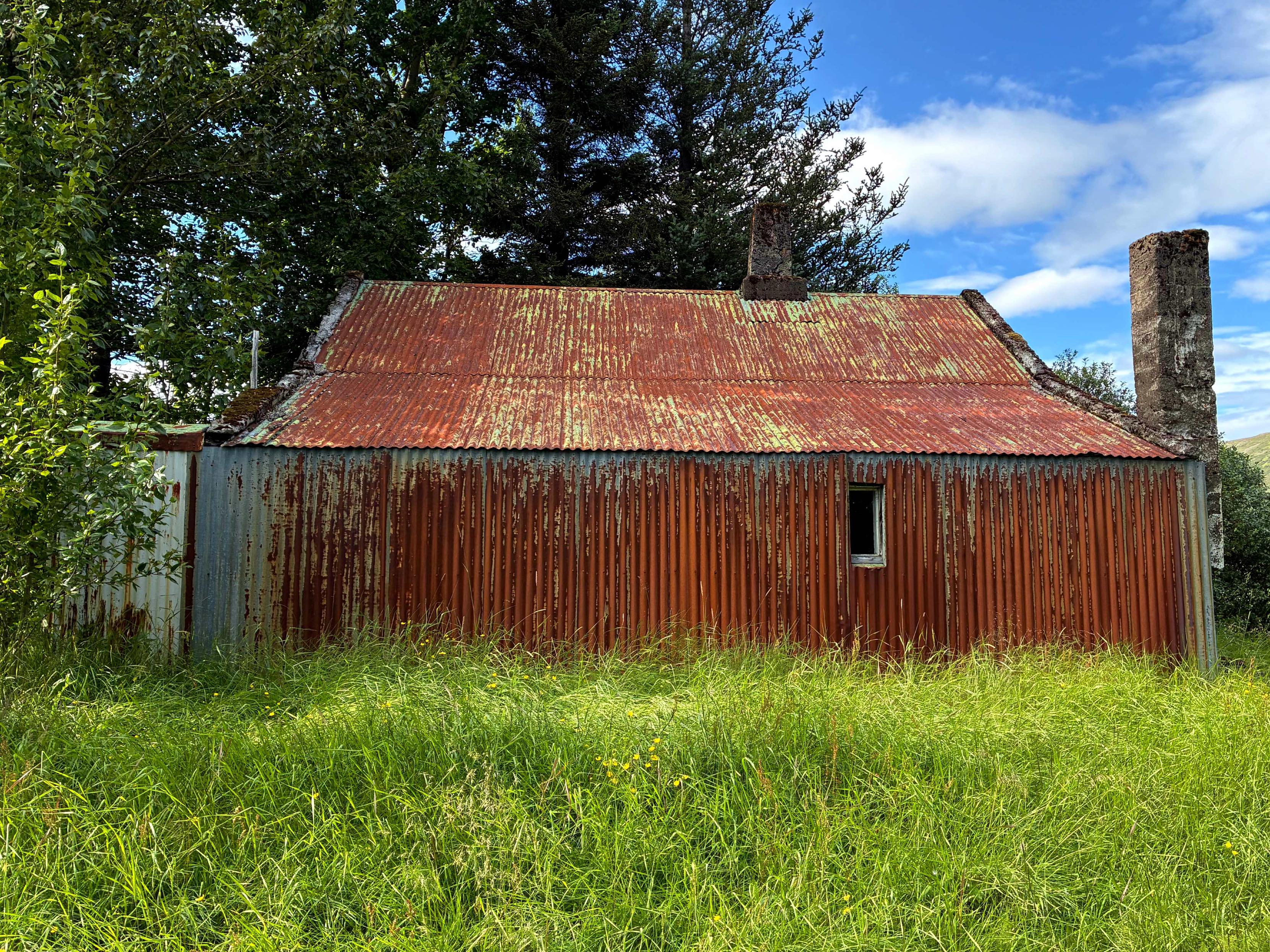 A very rusty abandoned house with a chimney.