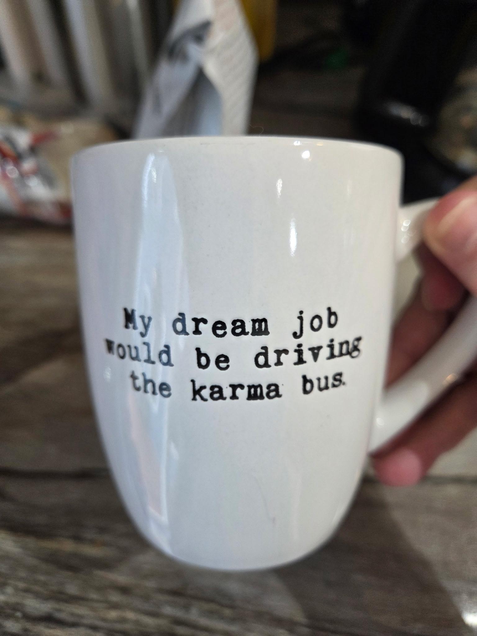 coffee cup says “My dream job would be driving the karma bus.”
