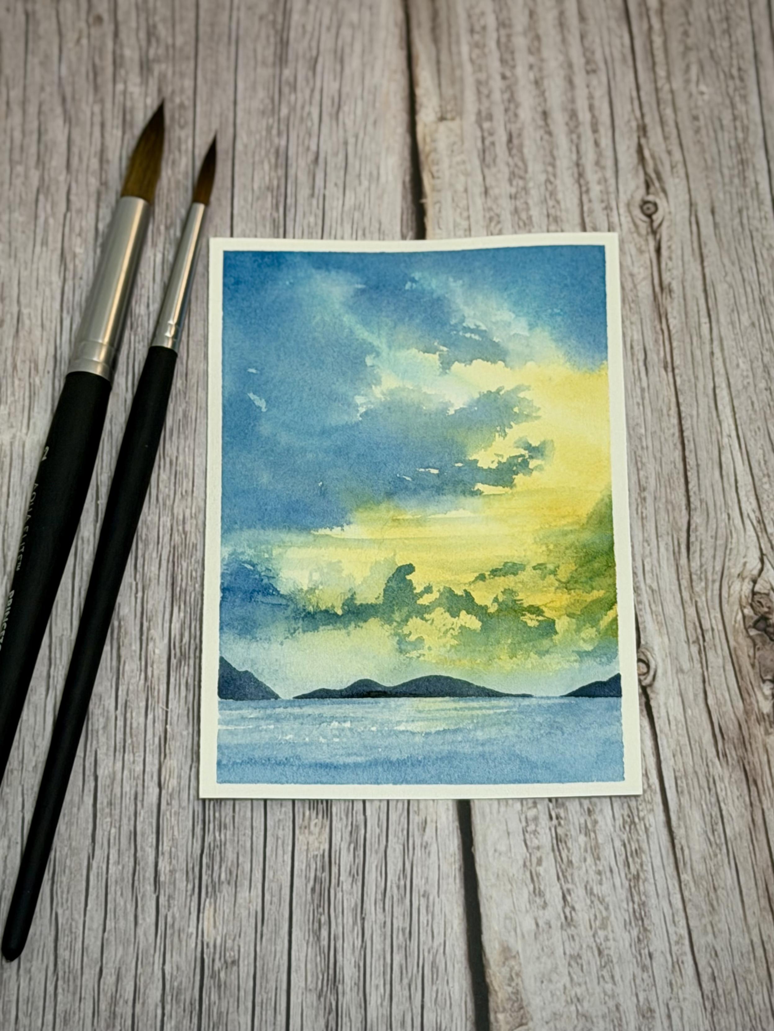 Painting of a big open shy with blue clouds and yellow sky in the distance. Small whisky clouds frame the mountains in the distance, covered in a light blue mist. Towards the bottom of the painting is the ocean.