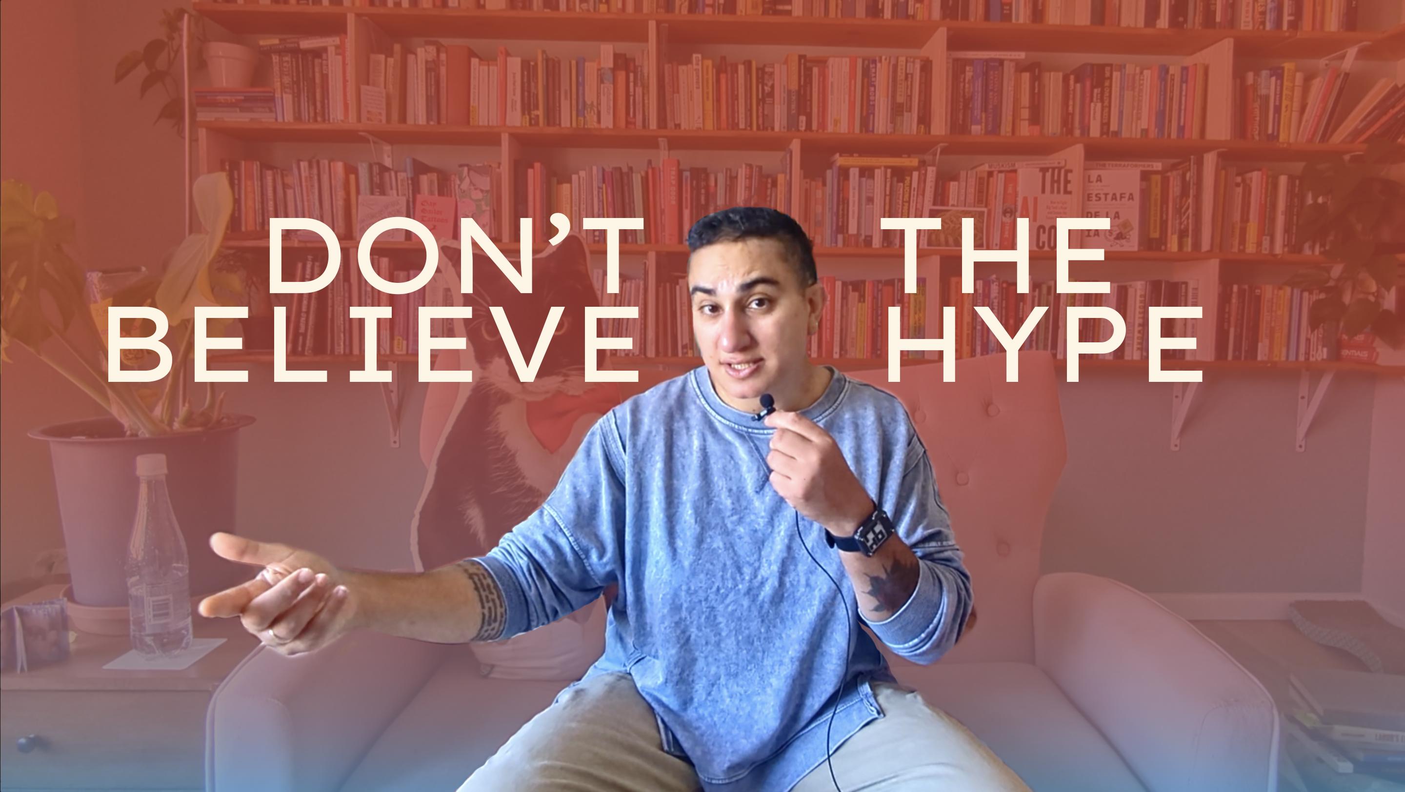 Cover image of a Youtube video showing Alex, a brown trans woman with curly black hair wearing a long-sleeve blue shirt and light tan pants. She is sitting on a chair and there is a red and blue overlay behind her, with the words "don't believe the hype" in bold capital letters.