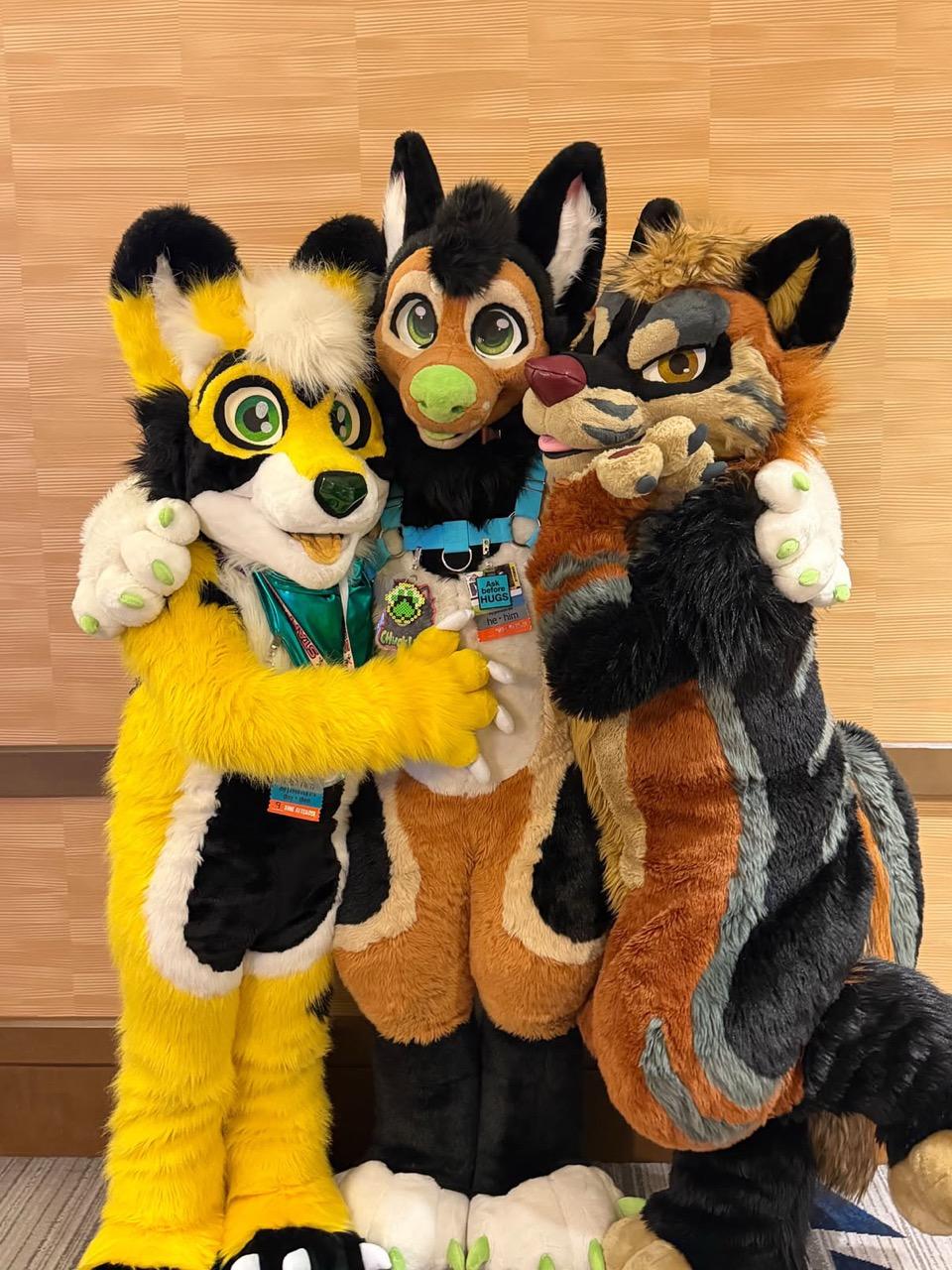 A group of fursuiters stand in front of a wall
