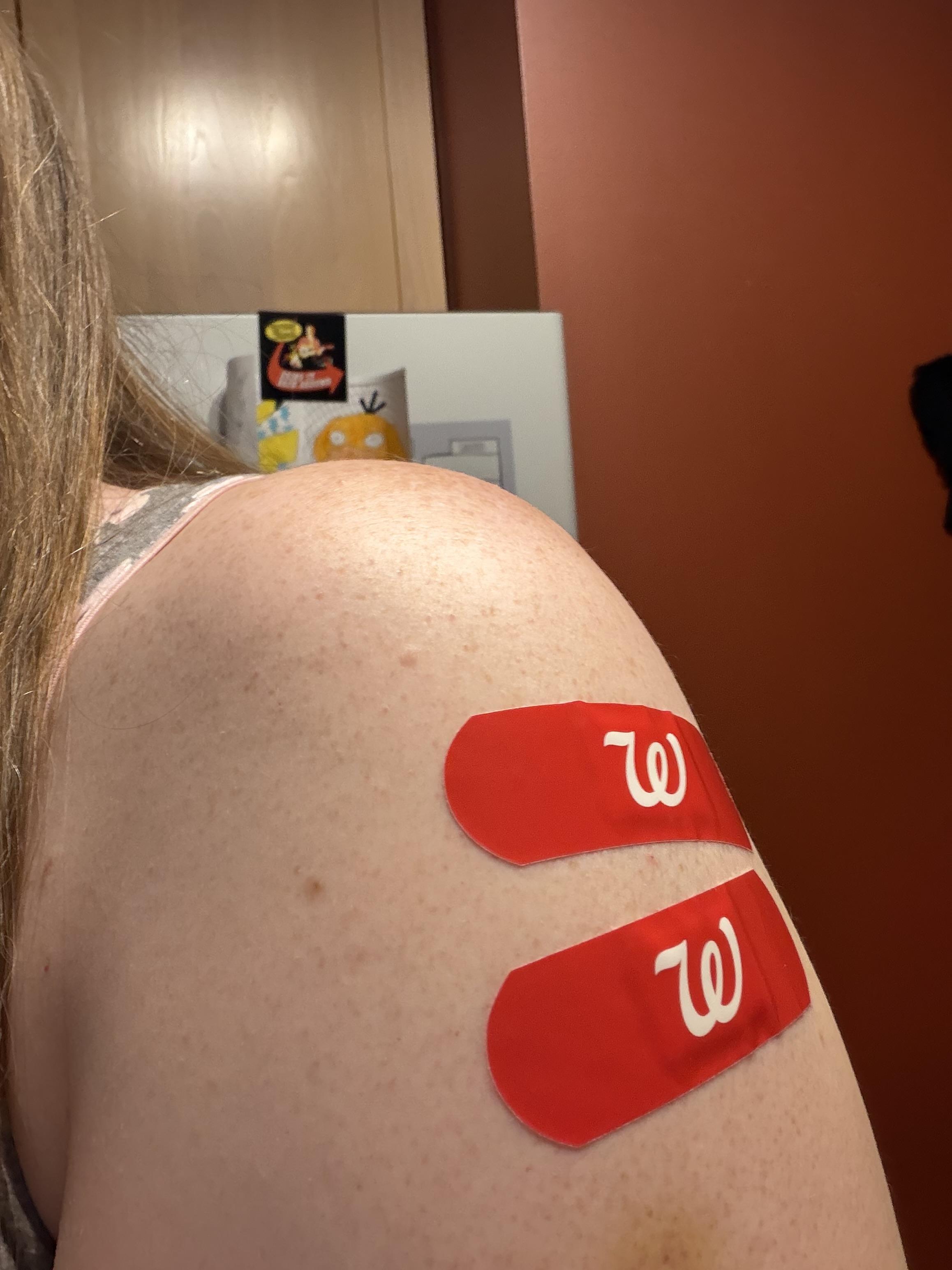Photograph of my left shoulder with two Walgreens bandaids on my upper arm where o received Covid 19 and flu vaccinations.