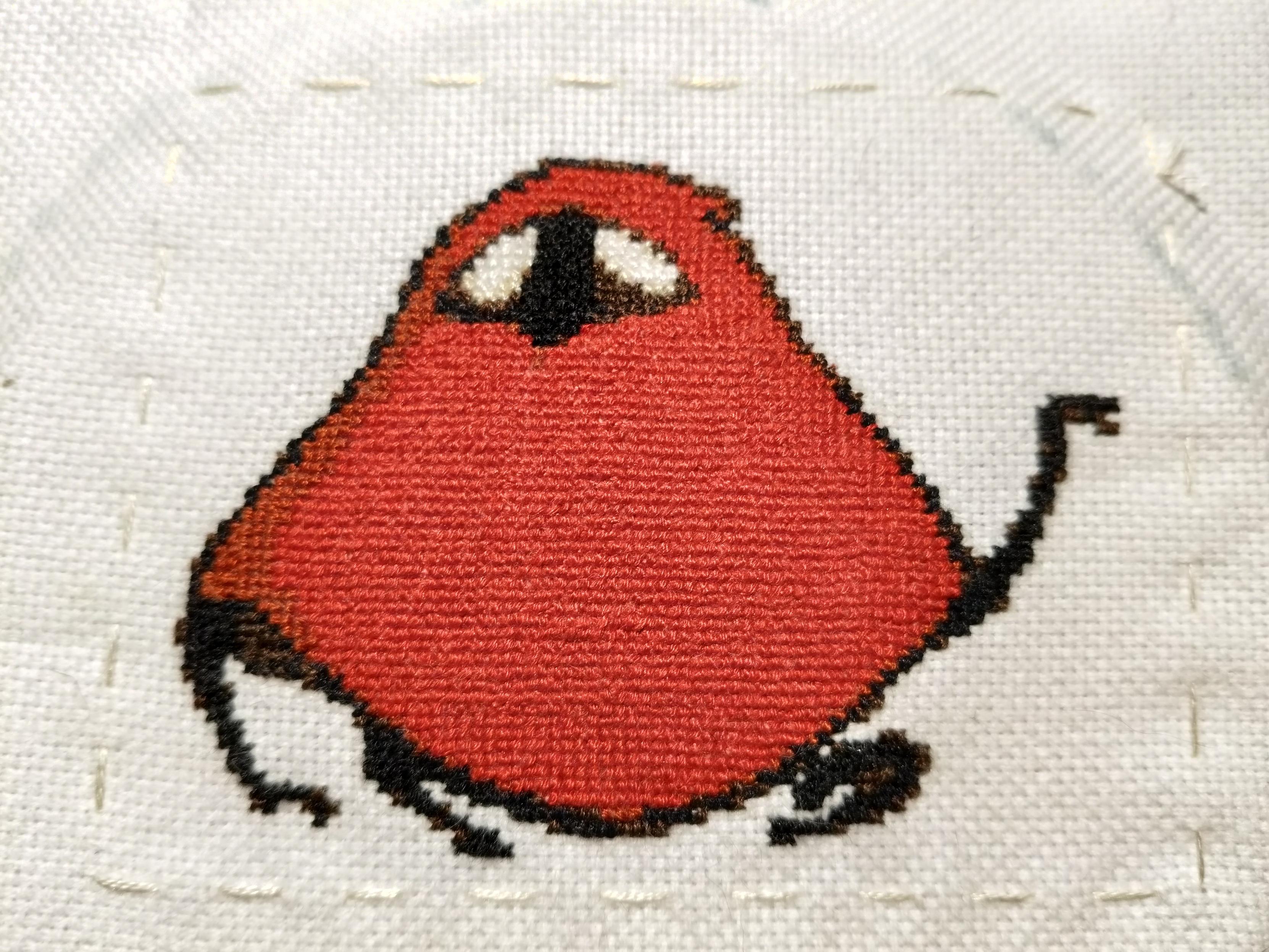 a cross stitch of the Seamstress character from the game Silksong. She is a bug with a big red cloak, white eyes and black limbs. she is stitched on white weave and a rough rectangular outline has been basted around her. in the top right the fabric is slightly blue from paint peeling off of the embroidery hoop.