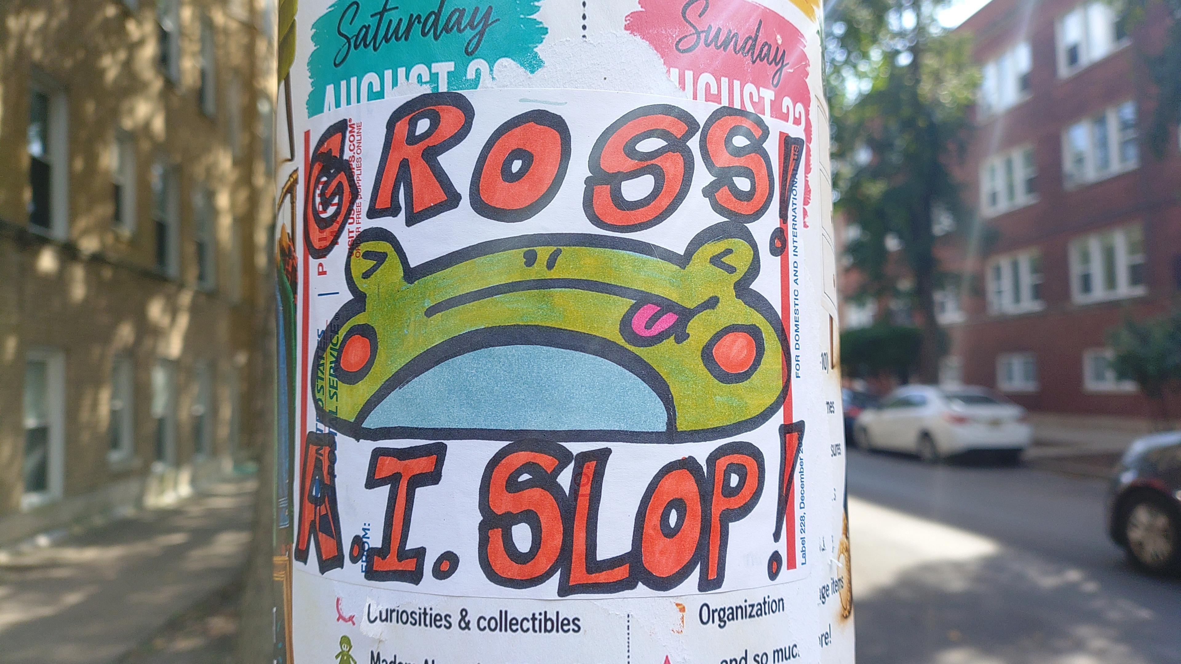 someone put up a yard sale sign on a utility pole, and someone else pasted over it with another sign that says "GROSS! A.I. SLOP!" + a cute drawing of a cartoon frog cringing about the slop.