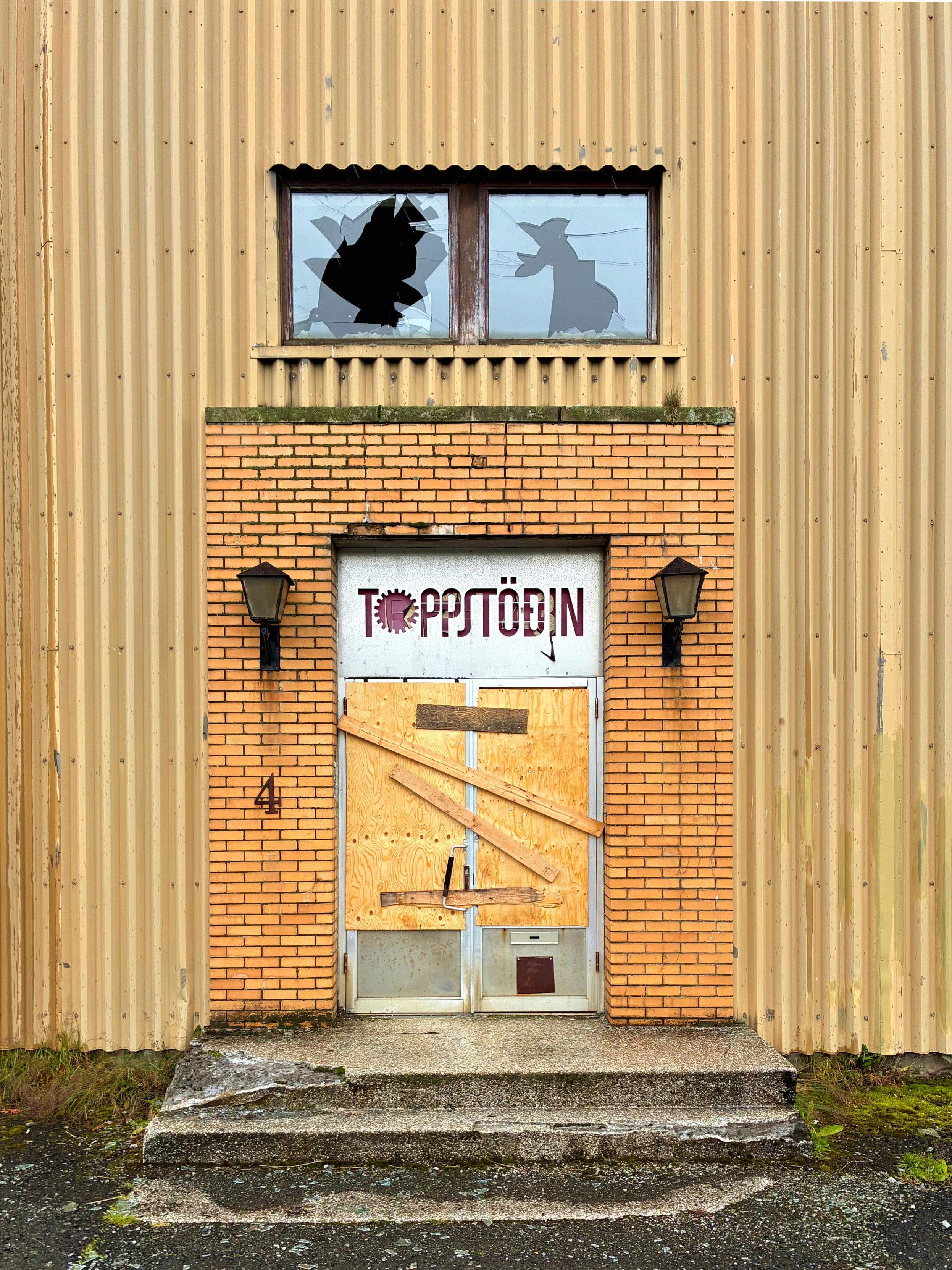 The door to an abandoned power station with broken windows.