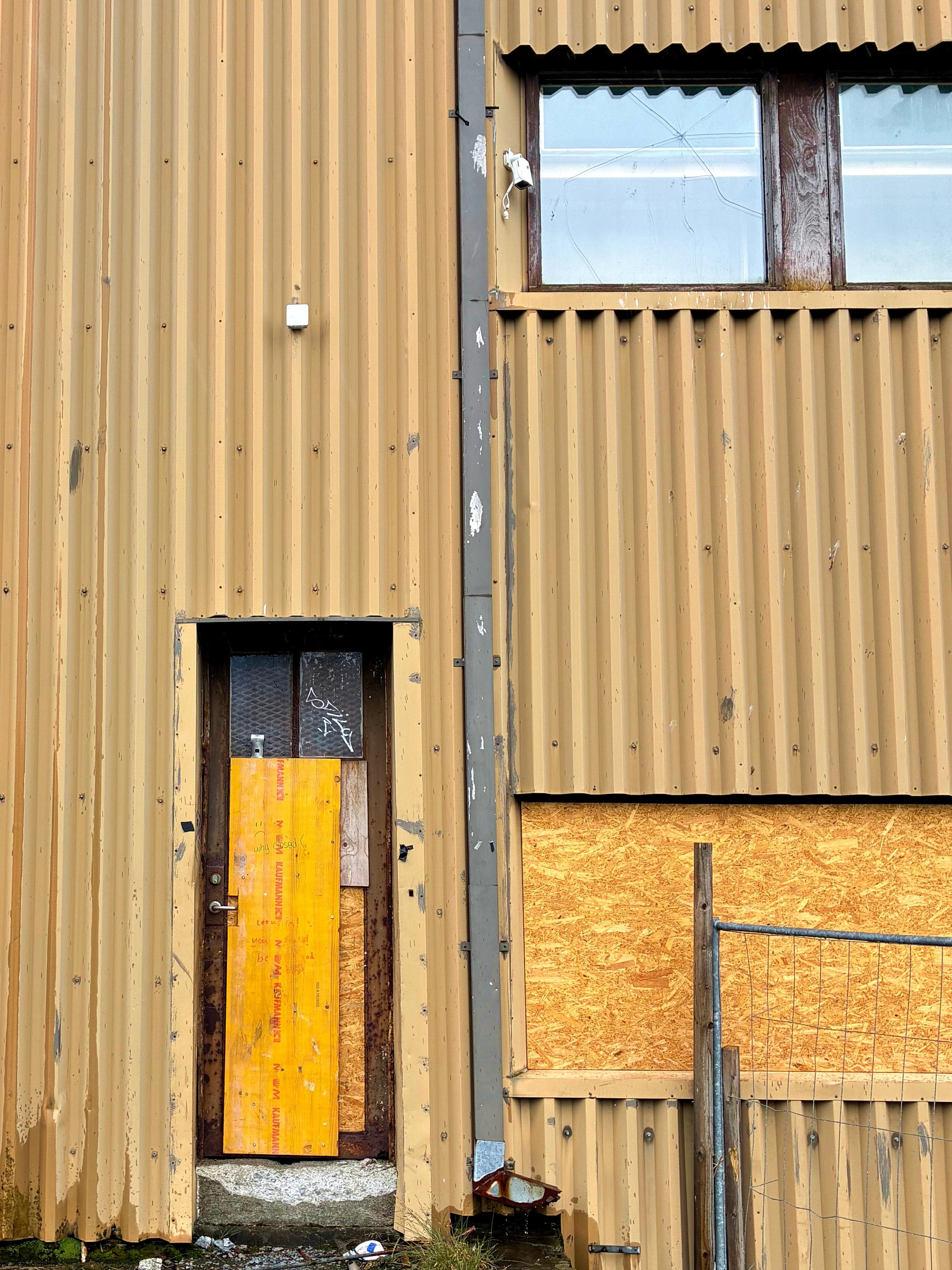 A boarded up door and windows on an abandoned building.