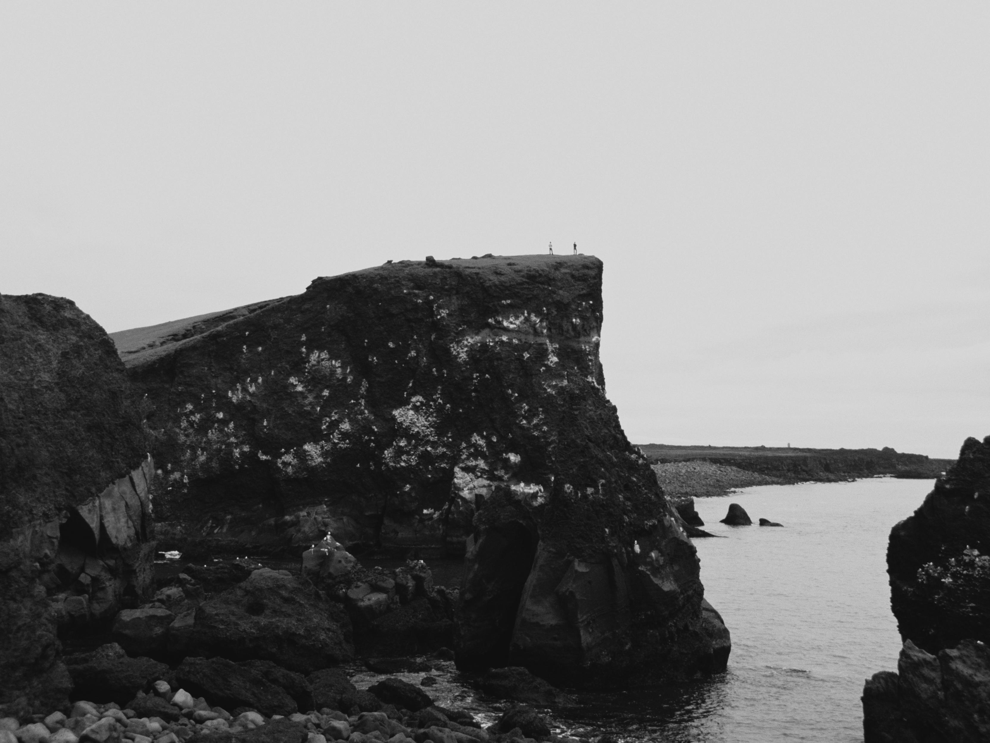 Two people standing near a cliff's edge.