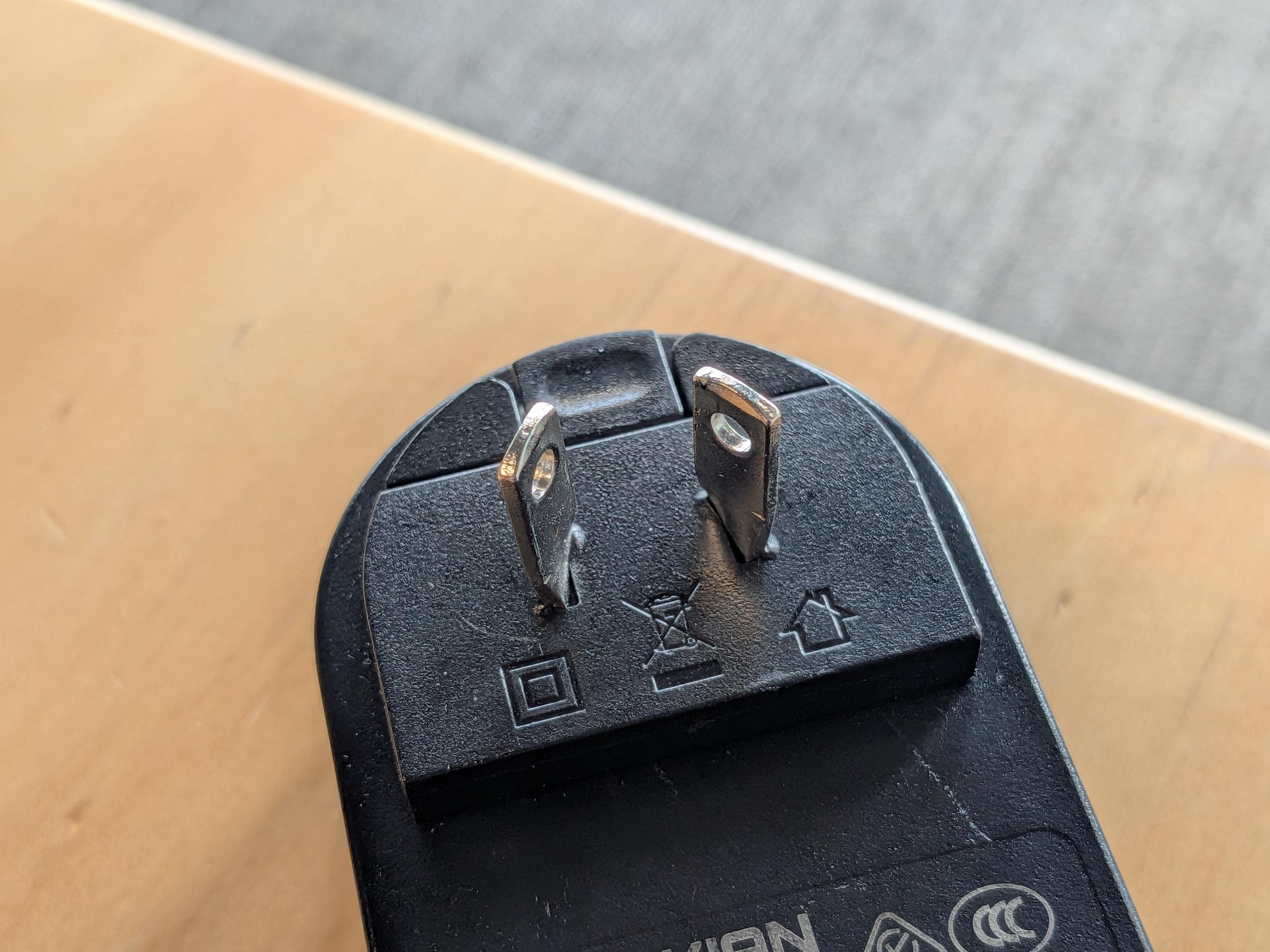 A plug in power adaptor where the straight US style AC connector has been bent to fit an angled Australian socket.