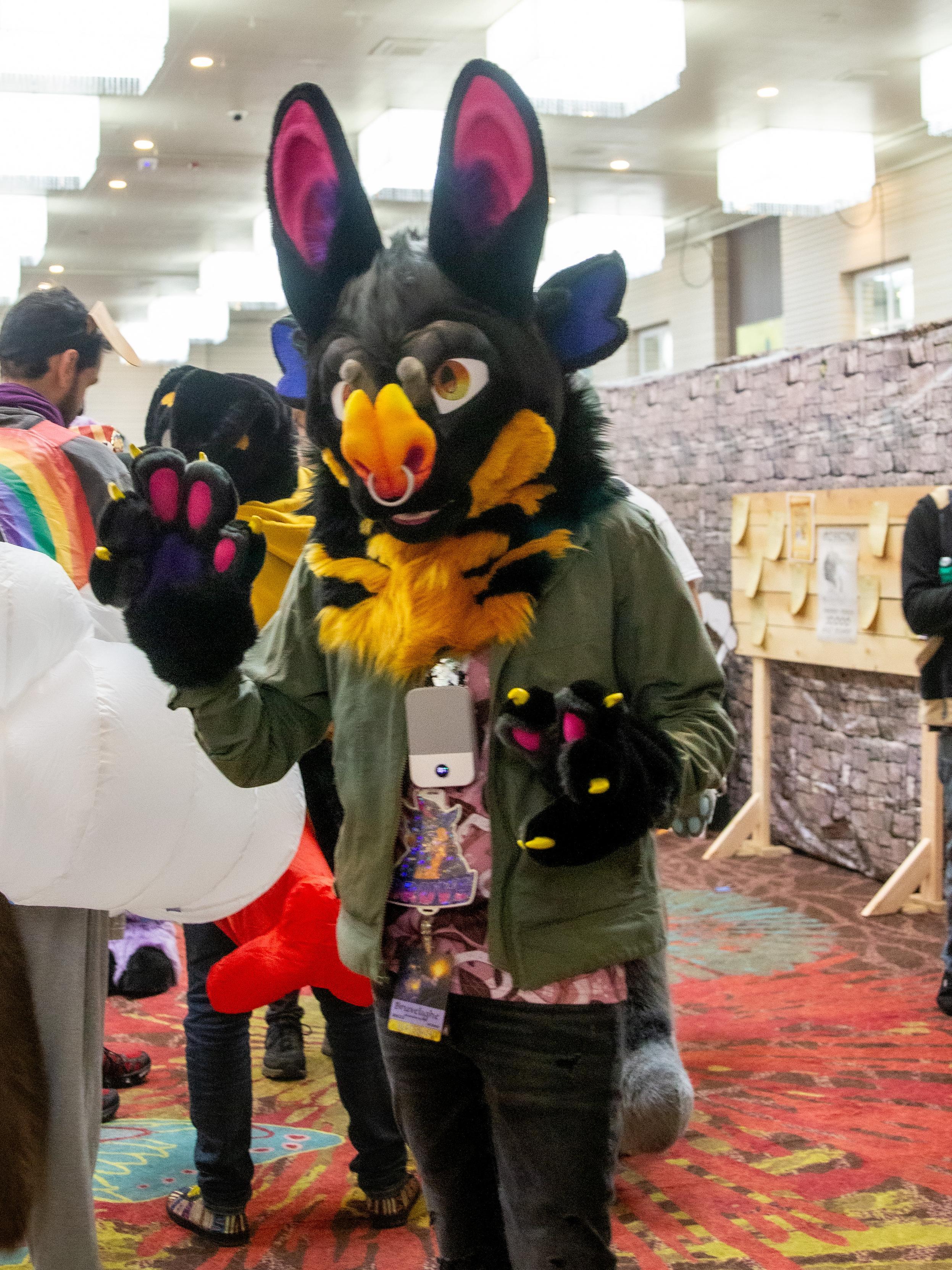 A photo of a bat fursuiter waving at the camera