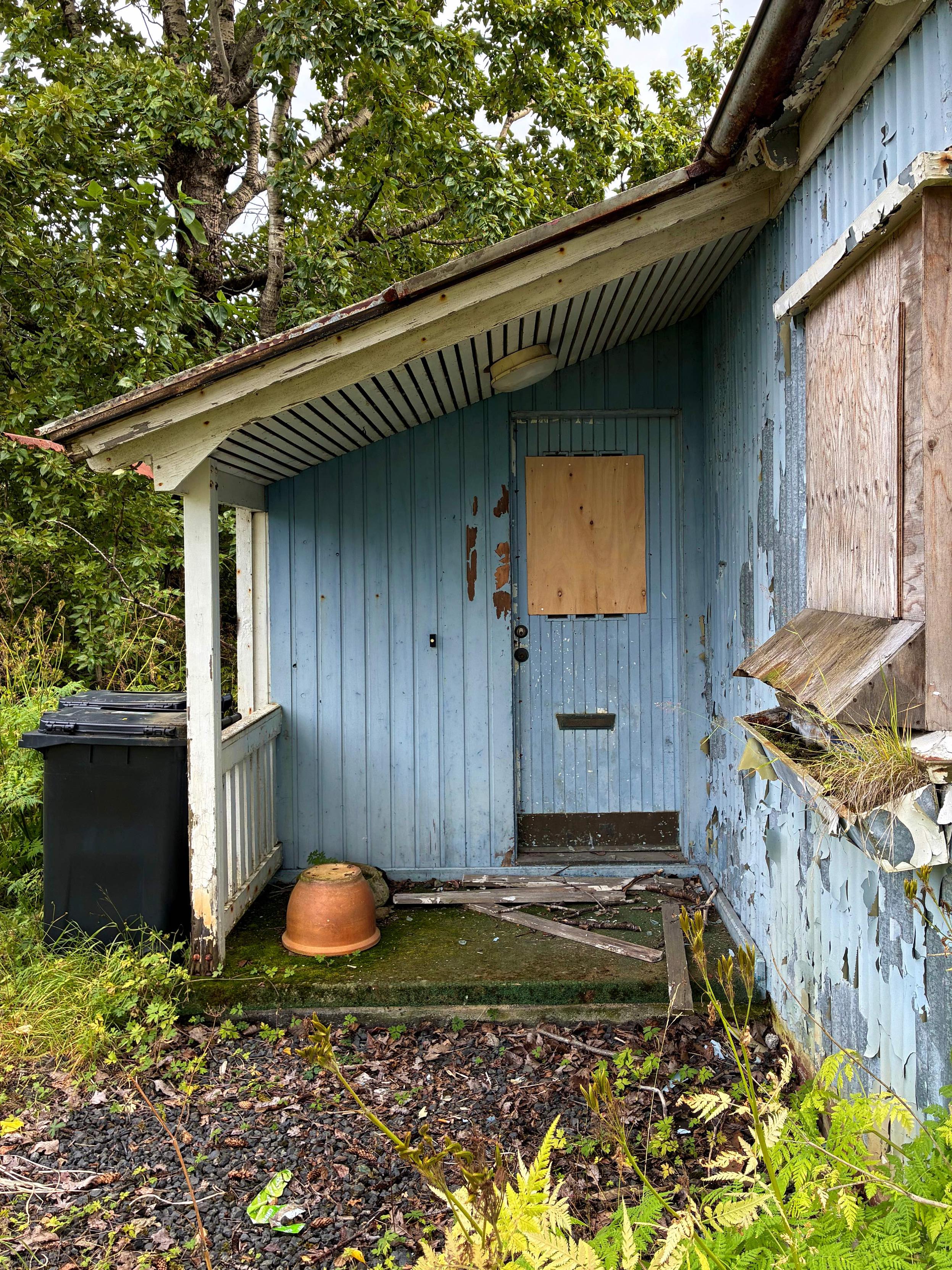 A door to an abandoned blue house.