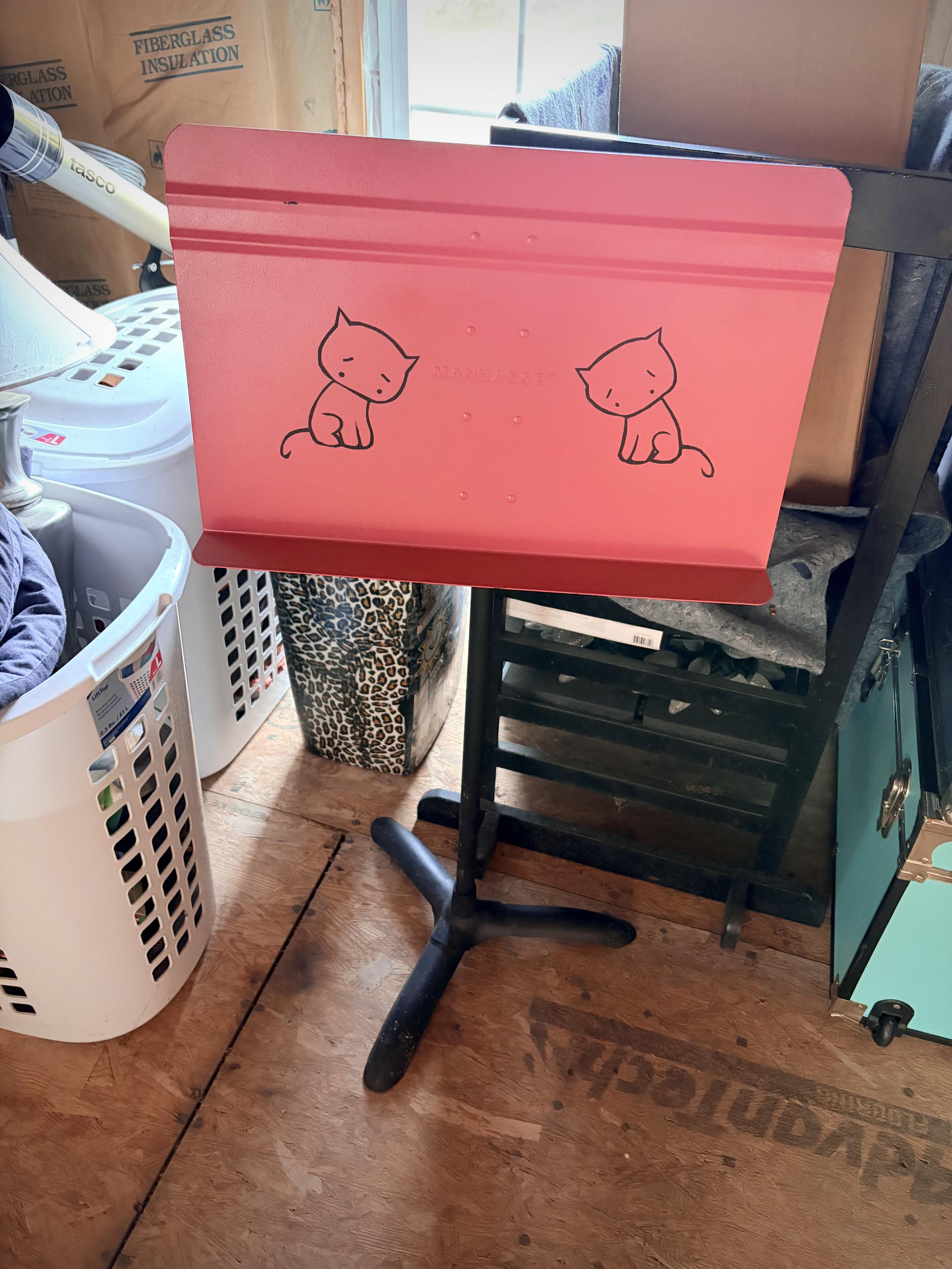 Black music stand painted bright pink with a couple of sad black kitties mirrored on the front.