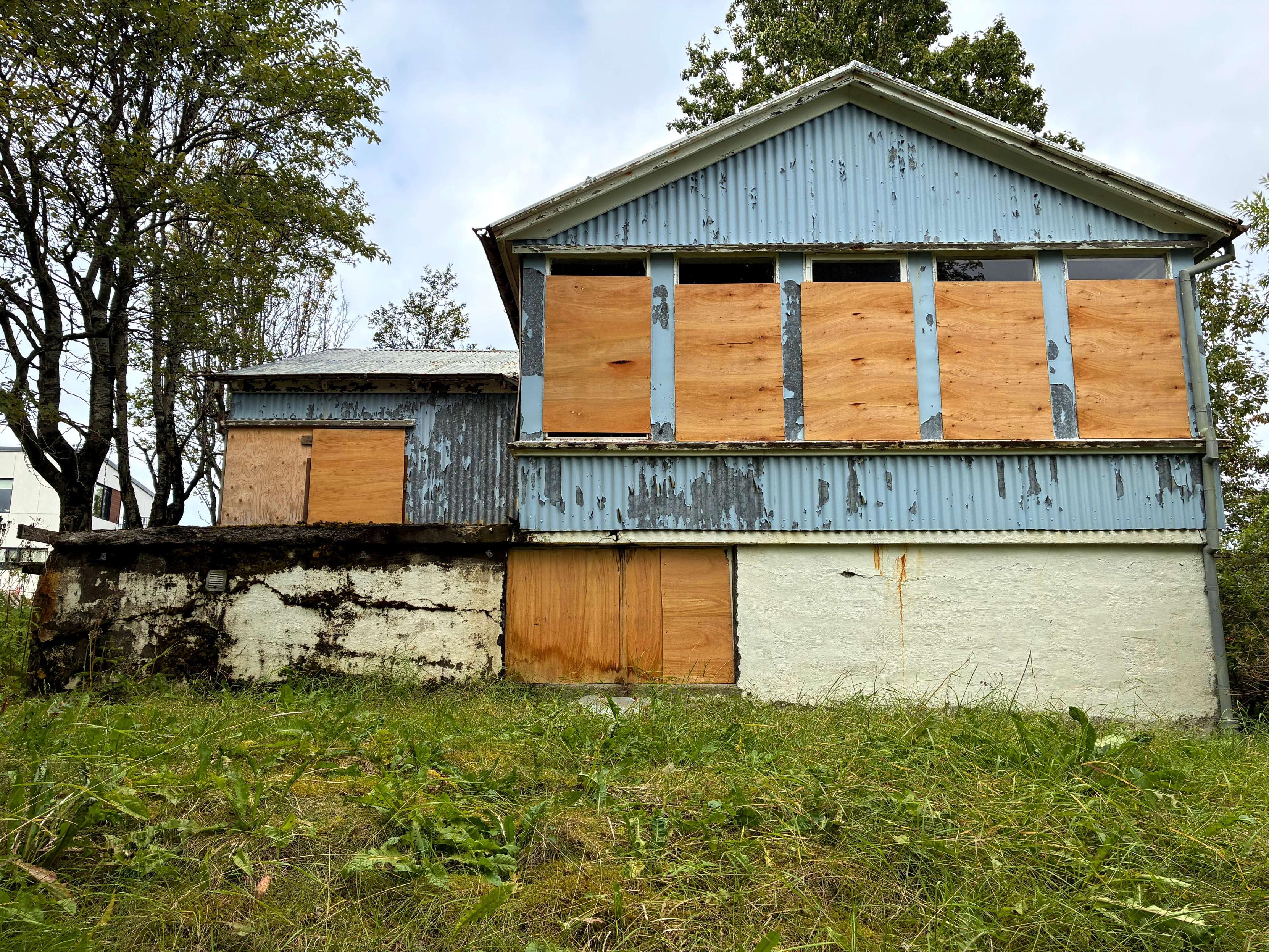 An abandoned house with boarded-up windows.