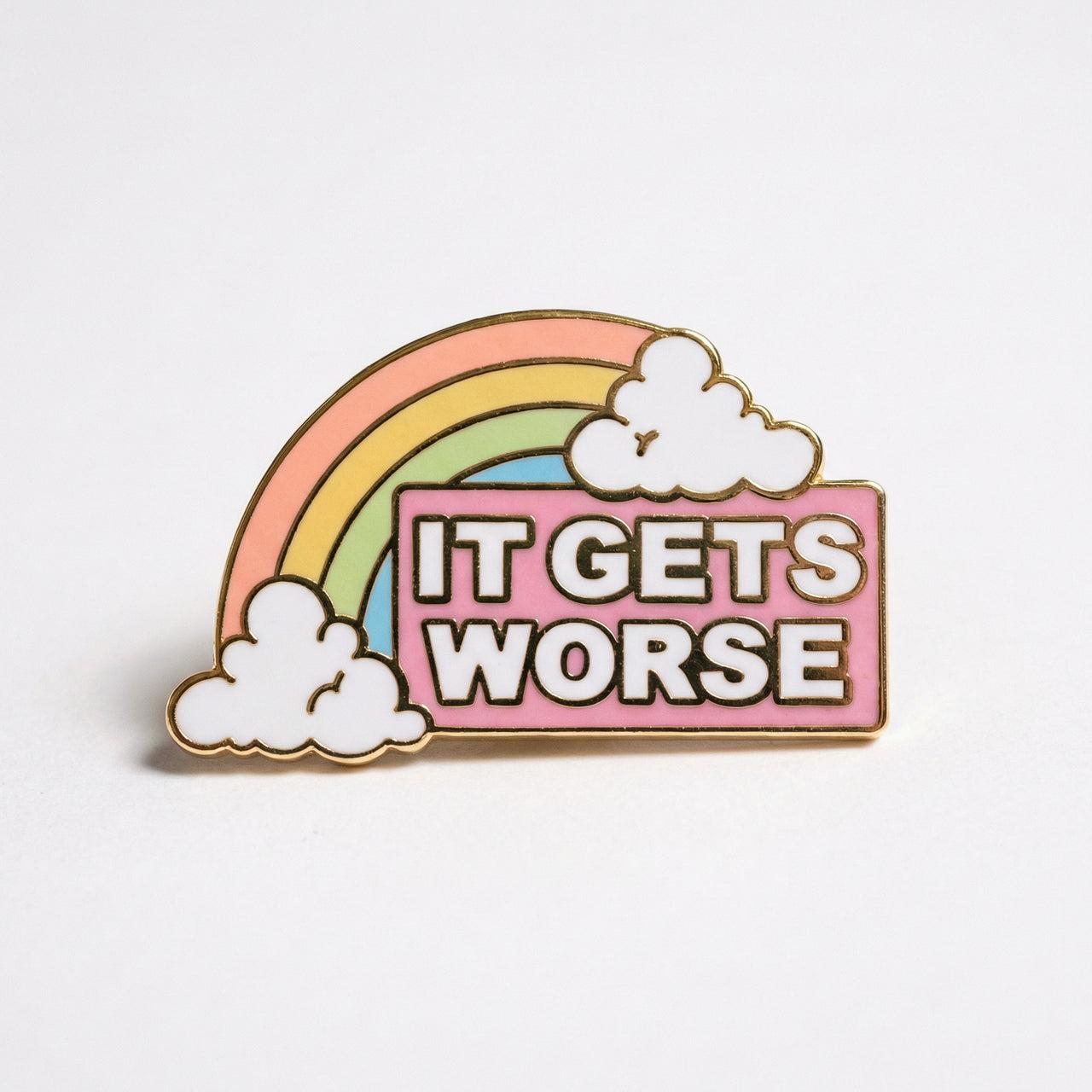 An enamel pin featuring a pastel rainbow arching over white clouds, with a pink banner in front reading "IT GETS WORSE" in white capital letters.