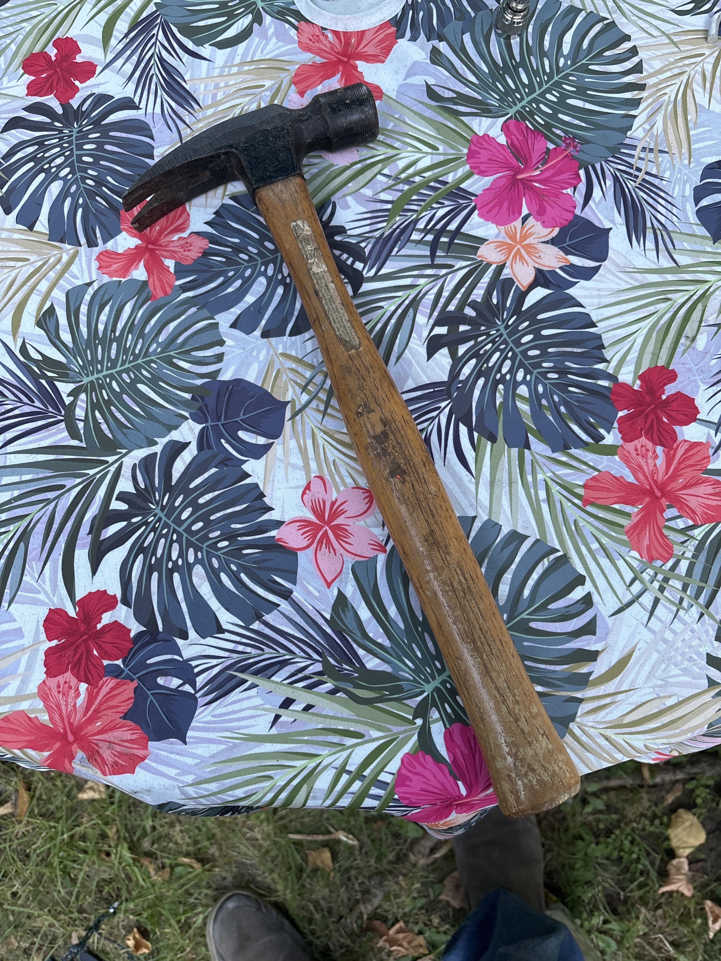 a large brown hammer on a floral patterned tablecloth