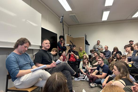 Referent Ingar Solty und Linken-Politiker Cem Ince in einem Seminarraum, in dem sich viele Menschen drängen