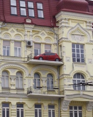 Red car parked on the balcony of a classical-looking building