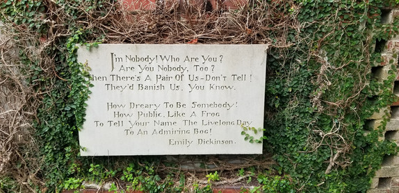Vines partially cover stone slab inscribed with poem.