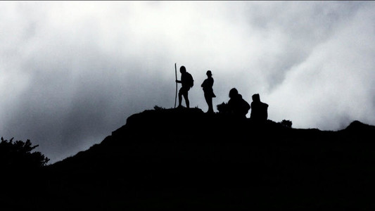 A group of people stand in silhouette on the top of a hill