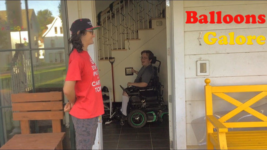 someone stands fromally in front of an open door where someone else in a wheelchair is laughing on the other side