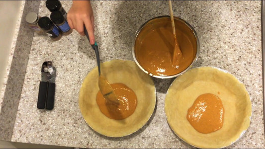 overhead view of pumpkin pies being filled