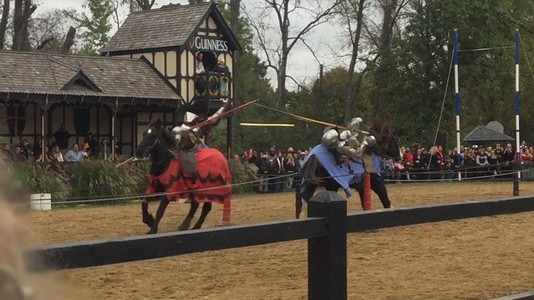 two people jousting are falling off their horses after an impact