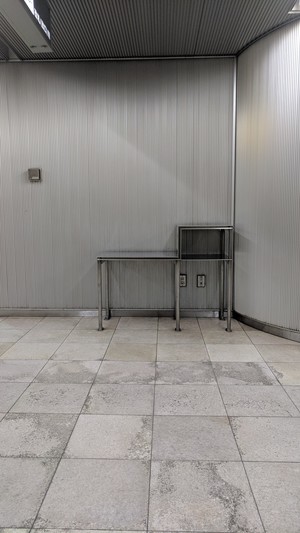 Three views of a steel table originally for public telephones now empty but cleaned and maintained by station staff.