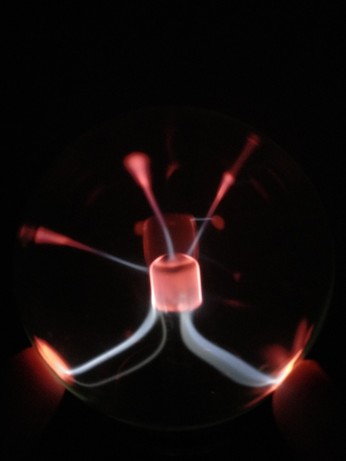 Close-up of a plasma globe focusing its discharges on a finger on the left- and right-bottom half of the glass dome.