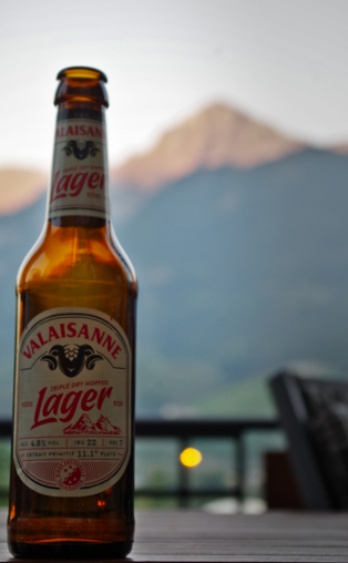 A bottle of Swiss beer. Mountains can be seen in the background.
