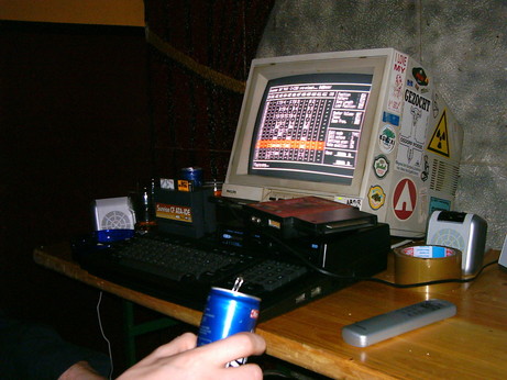 an MSX home-computer running #
MoonBlaster tracker from a Sunrise CompactFlash ATA-IDE interface, at an MSX Party, connected to a heavily stickered Philips MSX monitor, and a set of speakers.
A Philips Music Module is seen lying on top of the machine. The can in the hand, is quite likely an energy drink. ;)