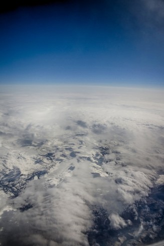 Snow-covered mountains of Norway, and the clouds above, as seen from an aeroplane in May 2014.