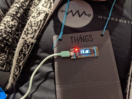 A small 128x32 OLED sewn on a lasercut badge