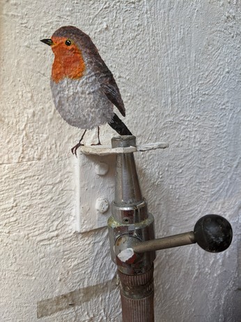 A painted bird mural on a water hose holder