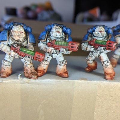Some model space marines in white and blue armour that have been painted to look weathered and dirty. 