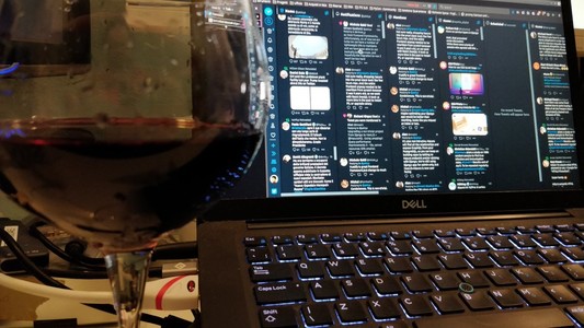 A glass of red wine, a laptop screen on the backgroud