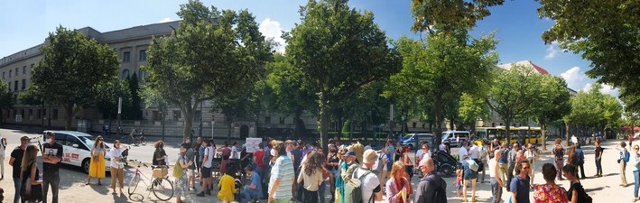 Unter den Linden, vor der russischen Botschaft stehen viele Menschen, manche mit Schildern. Links im Bild das RBB-Auto.